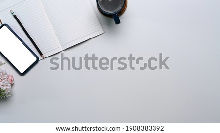 Top view of minimal workspace with empty notebook, smart phone and coffee cup. Copy space for your text or advertising content.