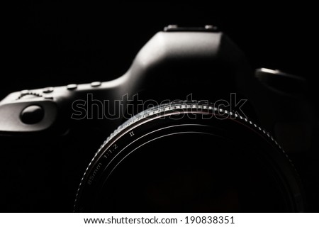 Professional modern DSLR camera low key image - Modern DSLR camera with a very wide aperture lens on