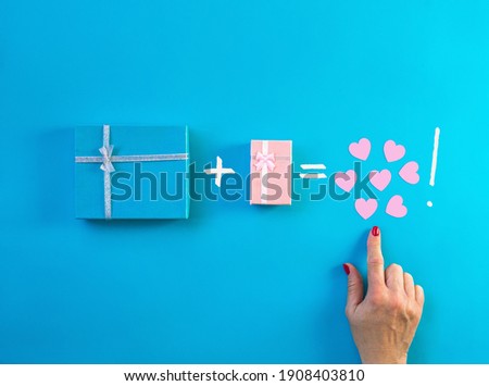 Gifts decorated with ribbon on blue background, woman hand finger points small hearts. Valentine, spring holidays, Christmas, birthday concept. Flat lay, blue and pink present boxes, top view. 