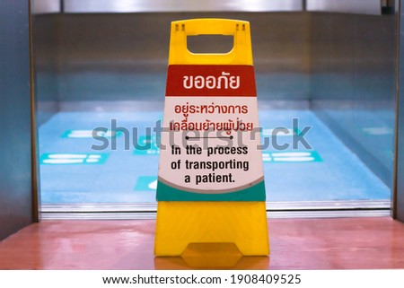 signboard announcement front of elevator for patient transporting give priority in emergency case with Thai letter saying : "Sorry, do not use this elevator. In the process of transporting a patient"