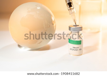 Glass globe and syringe with Covid-19 vaccine and beaker on white background . Global health care concept