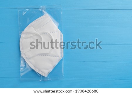 KN95 FPP2 medical respirator white mask medical equipment on blue wooden background. Plastic pack. Copyspace Royalty-Free Stock Photo #1908428680