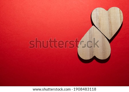 Wooden hearts placed on a red background. In the image there is room for text.