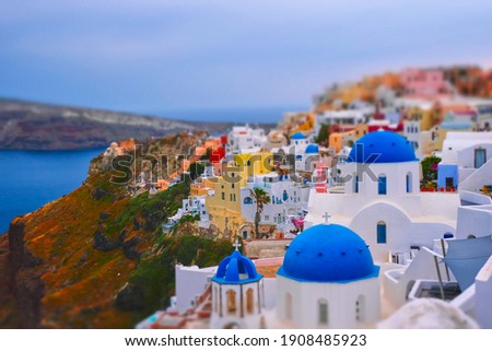 Famous greek iconic selfie spot tourist destination Oia village with traditional white houses and church in Santorini island on sunset in twilight, Greece. Toy camera tilt shift miniature effect Royalty-Free Stock Photo #1908485923