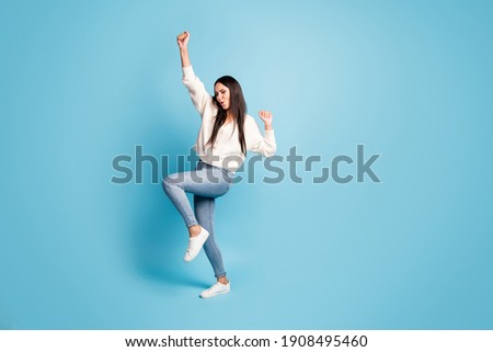 Full length portrait of funny adorable girl dancing raise knee hands isolated on blue color background
