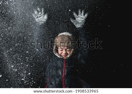 Photo of a boy in winter clothes in the evening in snowy frosty weather, playing in the dark