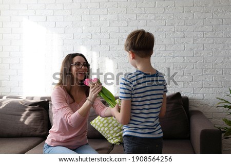 
boy gives pink tulips to mom. 8th march holiday concept