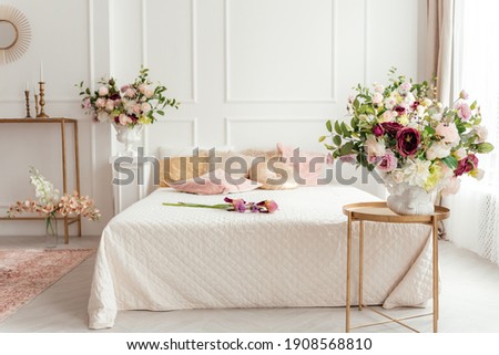 white bed in a bright bedroom decorated with spring flowers Royalty-Free Stock Photo #1908568810