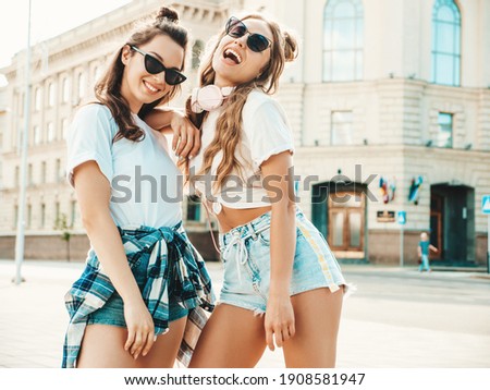 Portrait of two young beautiful smiling hipster female in trendy summer white t-shirt clothes.Sexy carefree women posing on street background. Positive models having fun, hugging and going crazy Royalty-Free Stock Photo #1908581947
