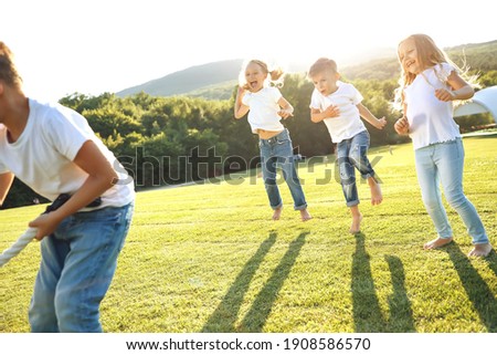 Four children sit on green grass on the ground and eat donuts and smile, sweet food, good friendship. High quality photo.