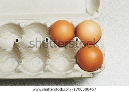 Culinary class in a kitchen. Three tinted brown chicken eggs in an open carton box on the table ready for cooking. Close-up view