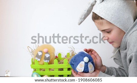 beautiful boy with bunny ears playing with a soft Easter toy rabbit in basket, slow motion, Happy Easter Day concept, fun celebrate on April holidays. Selective focus