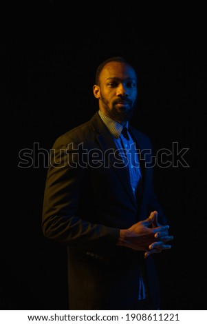 Portrait of young African-American man posing isolated on black background.