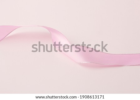 Pink ribbon isolated on a pink background, The campaign against breast cancer worldwide using the campaign symbol in the shape of a pink ribbon, copy space.
