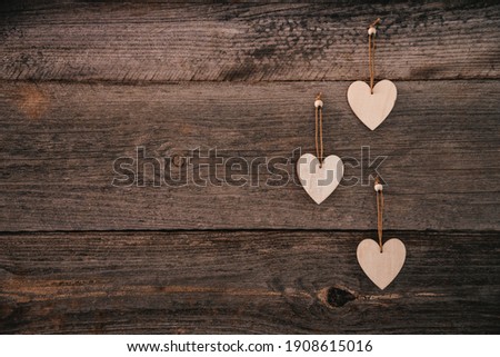 Valentine's Day background. Brown natural boards in grunge style with three wooden decorative hearts. Top view. Surface of table to shoot flatlay. Concept love, romantic relation. Copy space for text