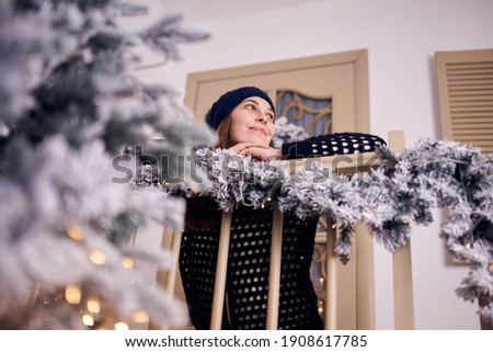 Woman in winter near a window at home with outdoors in the background.