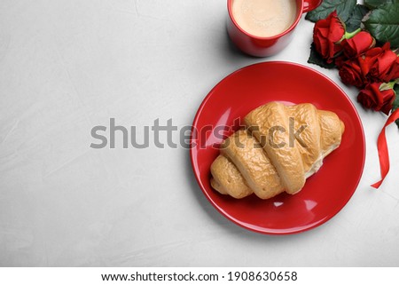 Cup of coffee, croissant and roses on light grey table, flat lay with space for text. Valentine's day breakfast