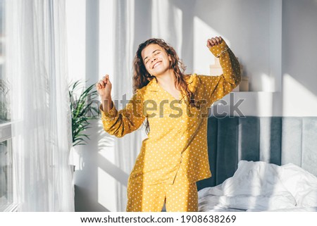 Woman in yellow pyjamas dancing in morning at home. Royalty-Free Stock Photo #1908638269