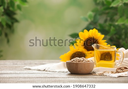 Sunflower oil and seeds on wooden table against blurred background, space for text Royalty-Free Stock Photo #1908647332