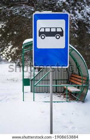 Bus stop in the middle of a beautiful winter road in the middle of the forest with a bus stop sign