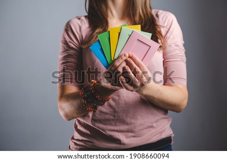 woman holds colorful photo frames in hands gray background. Hands holding colorful frames fot text, ad, memoris, your photos