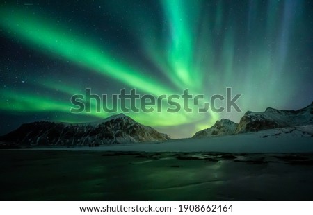 Northern Lights on the night sky. Aurora Borealis over Skagsanden beach on Lofoten Islands. Northern Norway. Wintertime starry sky. Royalty-Free Stock Photo #1908662464