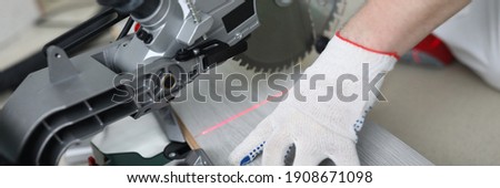 Close-up of professional foreman working with metal electrical equipment. Man in protective white gloves for work. Detailed picture. Laminate on floor. Renovation and construction site concept