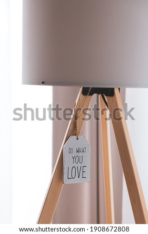 Concept image with the text Do What You Love hanged on a wooden plate under a lamp