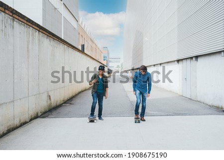 Two sportive men outdoors spending time enjoying skateboarding together 