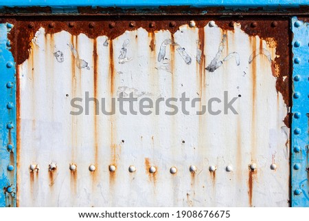 White peeling paint rust texture grunge background of a white painted vintage cast iron textured panel frame with metal rivets, stock photo image