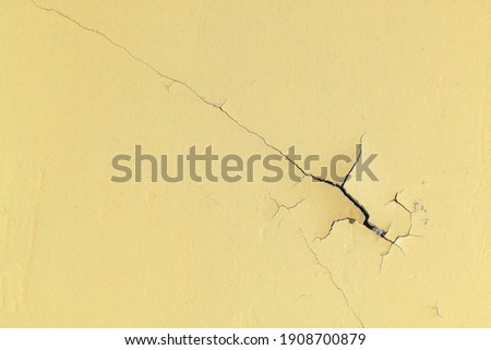 Peeling Paint on the Yellow Wall or Floor. Long Crack with Flaky Edges. Repair Required. Abandoned Premises. Conceptual Background. CloseUp. Royalty-Free Stock Photo #1908700879