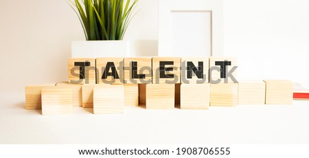 Wooden cubes with letters on a white table. The word is TALENT. White background.