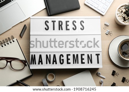 Flat lay composition of lightbox with phrase Stress Management on wooden table