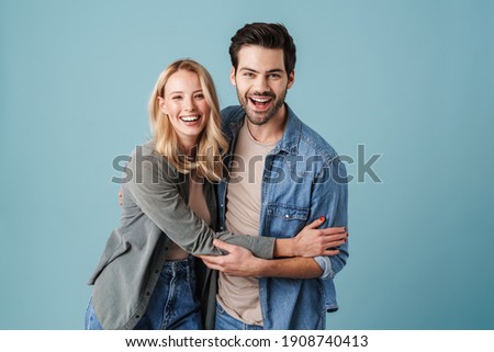 Young beautiful caucasian man and woman smiling and hugging at camera isolated over blue background