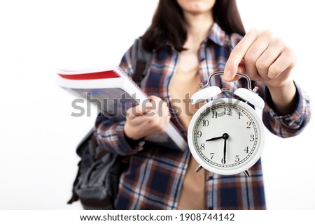 young female student is holding a clock in her hand. back to school concept. University and foreign language education concept banner, background. Copy space for advertisement.
