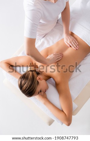high angle view of masseur massaging back of young woman on massage table Royalty-Free Stock Photo #1908747793