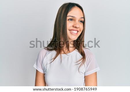 Young brunette woman wearing casual white t shirt looking to side, relax profile pose with natural face and confident smile. 