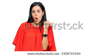 Beautiful young woman wearing casual clothes surprised pointing with hand finger to the side, open mouth amazed expression. 