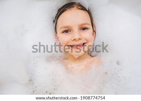 Close-up portrait of smiling girl in white foam in the bath. 