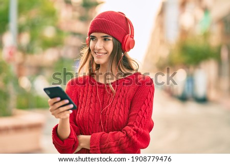 Young hispanic woman using smartphone and headphones at the city.