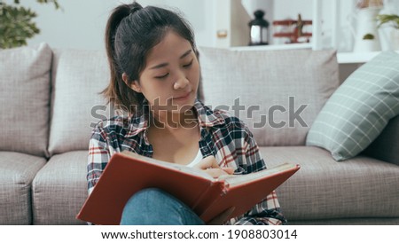closeup asian woman with attentive look is keeping diary and touching chin with pencil while thinking about what to write in the journal. Royalty-Free Stock Photo #1908803014