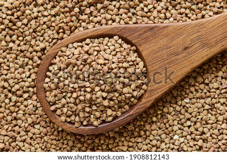 Uncooked dried buckwheat in a wooden spoon, close up, macro