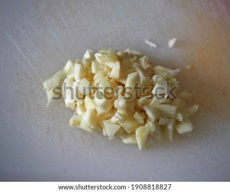 Garlic minced on a white plastic cutting board