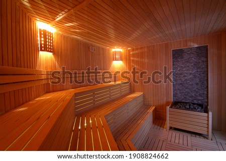 Seat in sauna room. Empty wooden steam room with stone heater.Sauna room for good health. Sauna room with traditional sauna accessories.Healthy and spa life style. Royalty-Free Stock Photo #1908824662