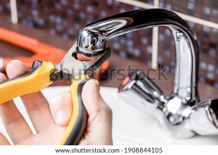 plumbing faucet repair concept. plumber using wrench tool and pliers to adjusting tap leak at bathroom. diy plumber conceptual. Royalty-Free Stock Photo #1908844105