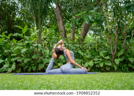 Portrait of a young woman doing yoga in the garden for a workout. Concept of lifestyle fitness and healthy. Asian women are practicing yoga in the park. Royalty-Free Stock Photo #1908852352