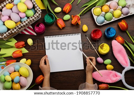 Stylish background with colorful easter eggs pastel colors on wooden background. Kid holding paint brush in hand. Flat lay, top view, mockup, overhead, template