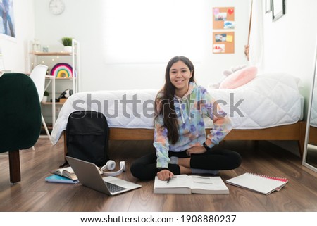 Adorable teenager girl taking notes from her school books. Happy caucasian adolescent girl studying and doing her school homework