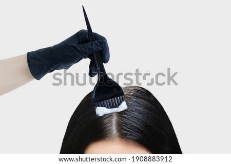 Dyeing gray hair. Brush in hand with paint dyes black hair. White background. Royalty-Free Stock Photo #1908883912