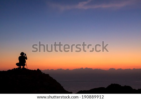 Man on top of the mountain taking photographic at sun rise 